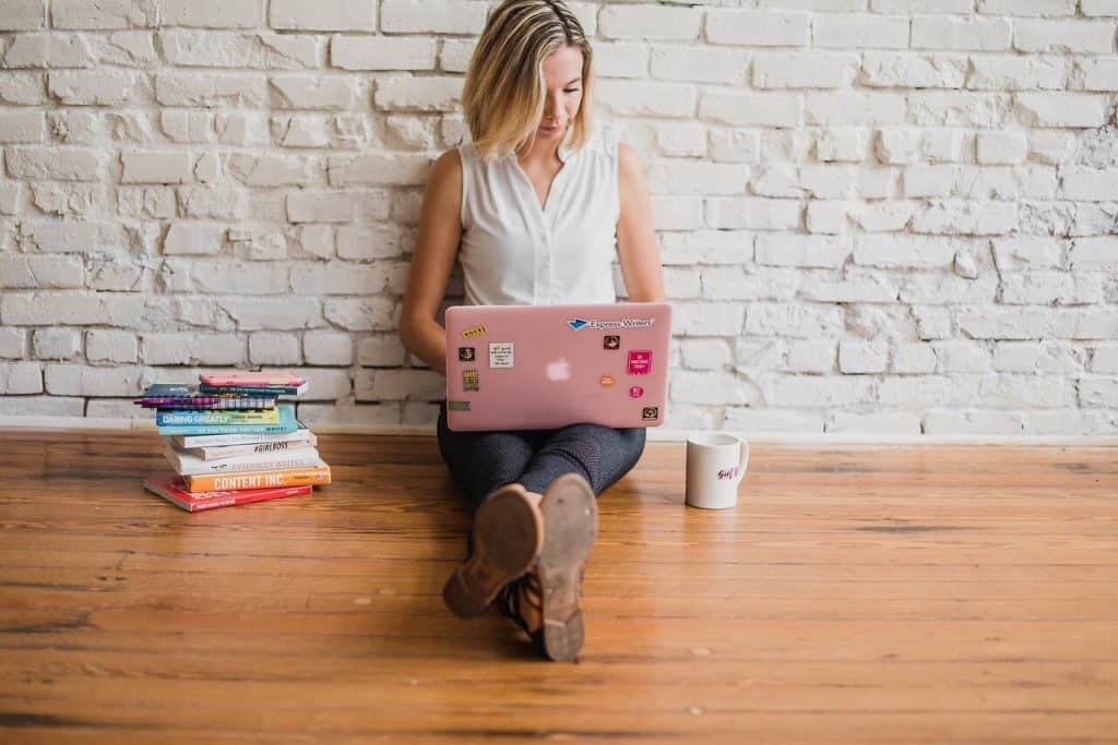 Girl typing on a laptop on the floor - how to become a freelance grant writer