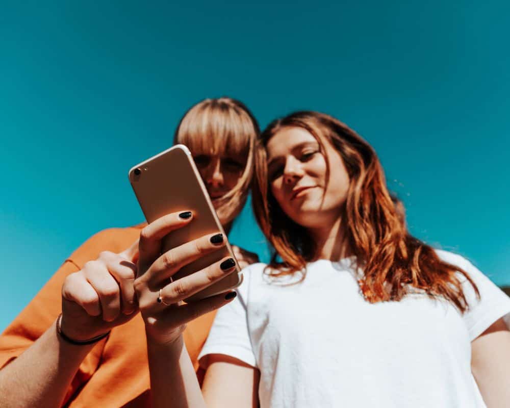 Can Someone See If You Screen Record Their Instagram Story? two girls looking at a mobile phone