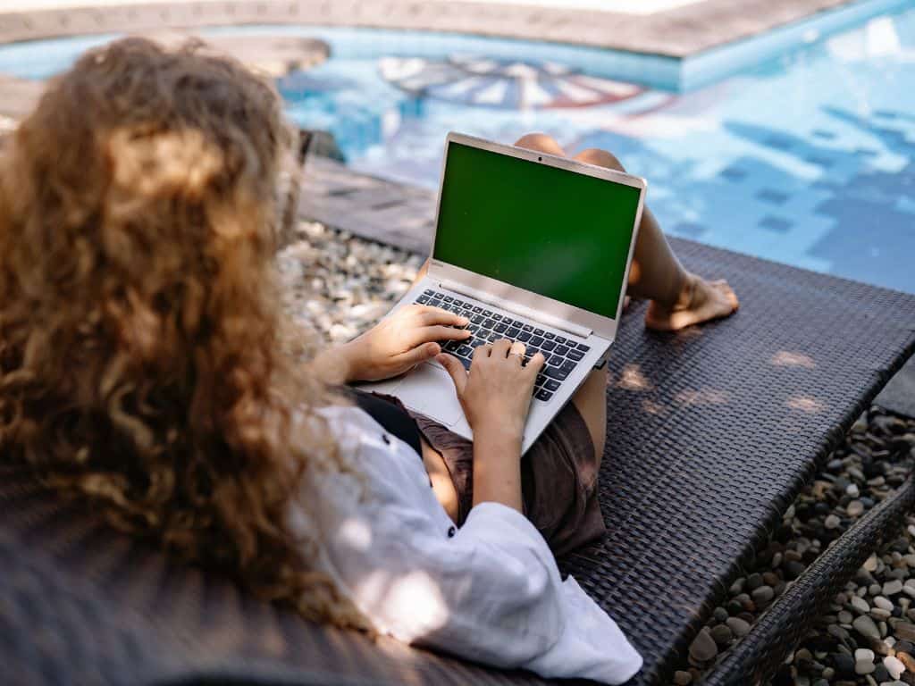 lady on her laptop by a pool