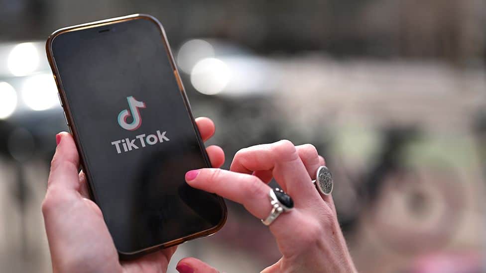 baddie usernames for tiktok: an image of a lady opening the tiktok app on her phone