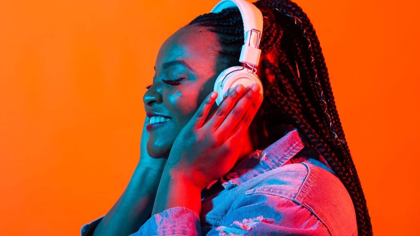 A  woman smiling while listening to a music with her headphone