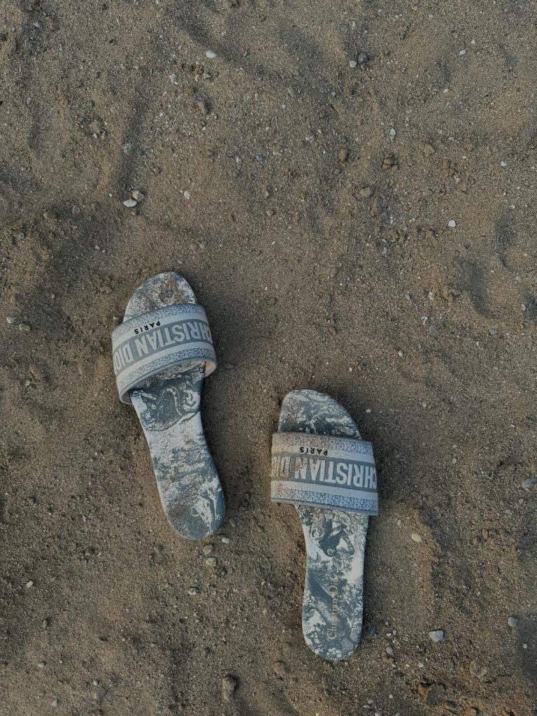 Christian Dior flats with beach sand strewn all over it