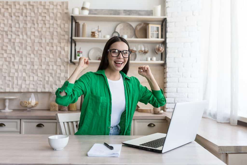 Freelancing Work From Home Part Time: Woman sitting at home in front of her laptop enjoying success