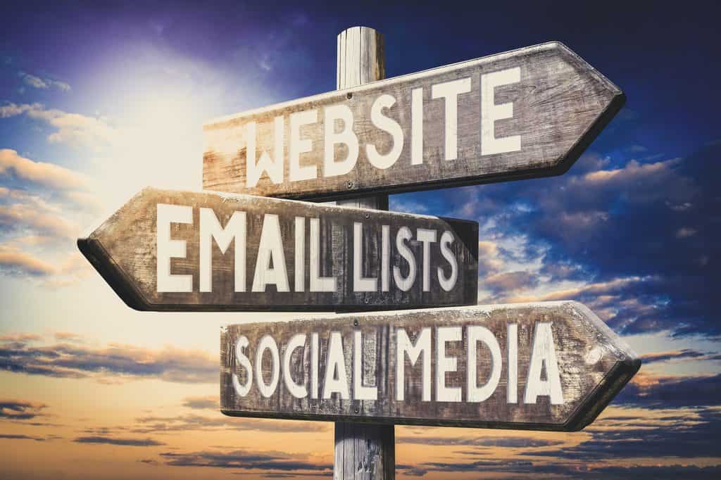 a poll with 3 directional signages on it indicating Website, email lists and social media in directions