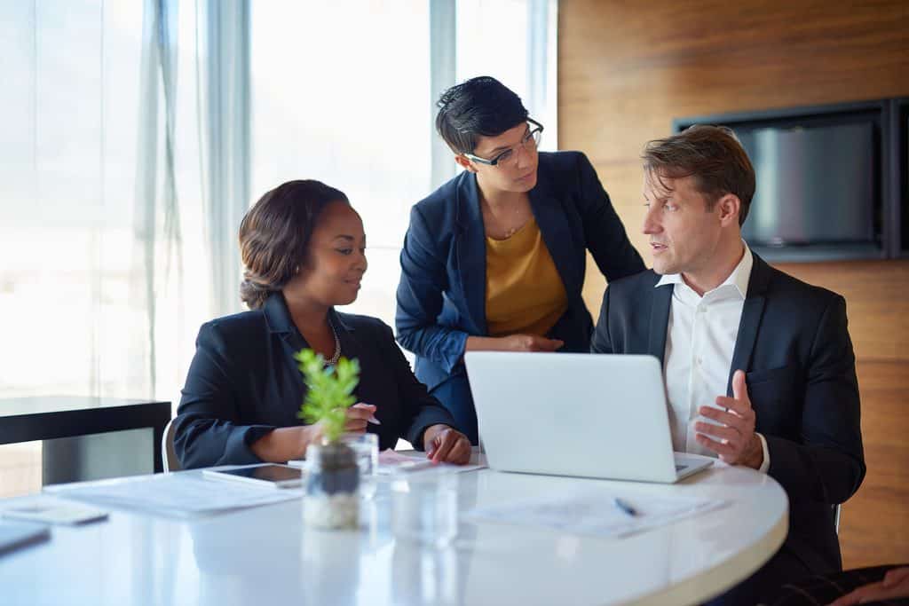 Business professionals discussing a client project around a laptop