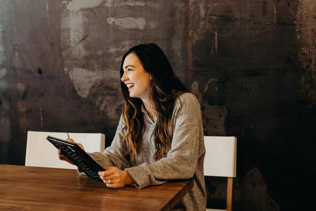 Freelance rates for beginners: A girl holding a tab, smiling