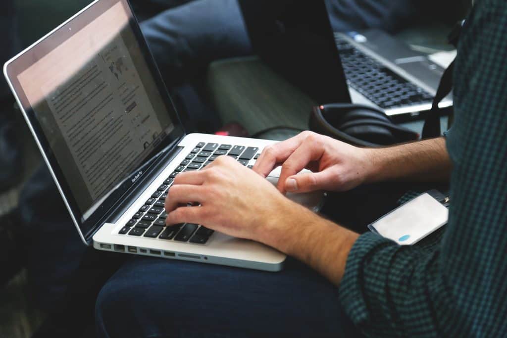 Freelancer typing a professional rate increase message on a laptop, part of how to raise freelance rates