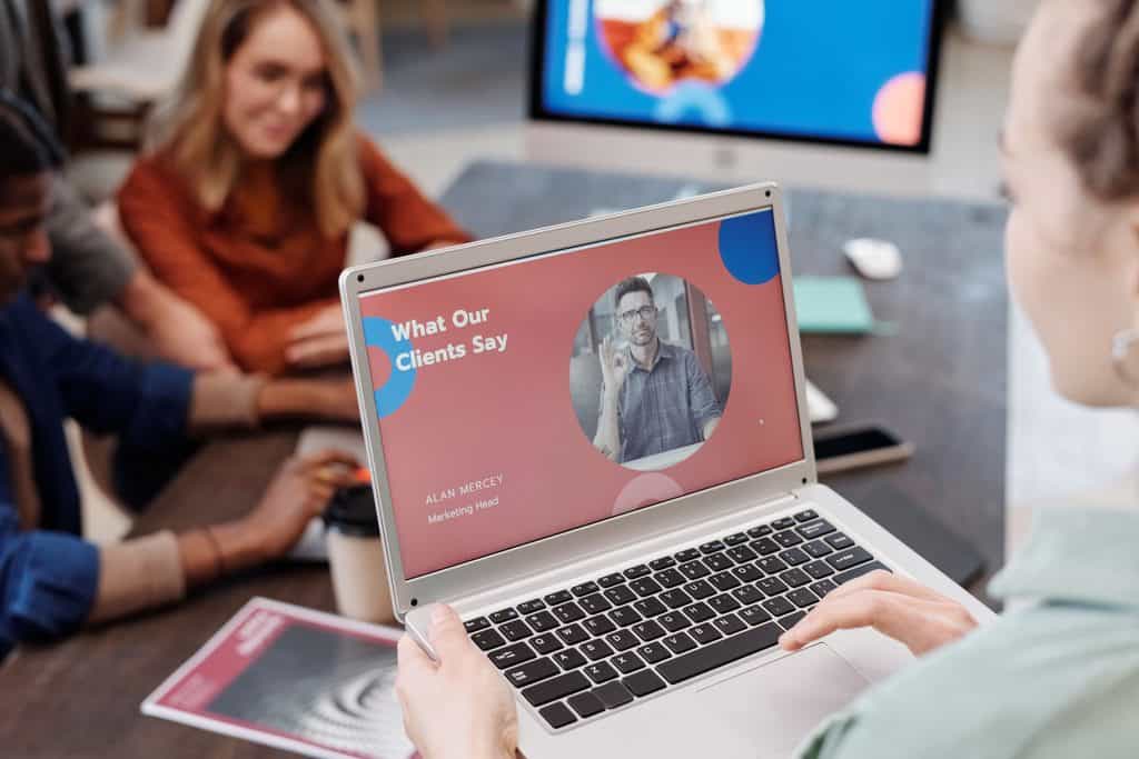Client testimonial presentation displayed on a laptop during a team meeting