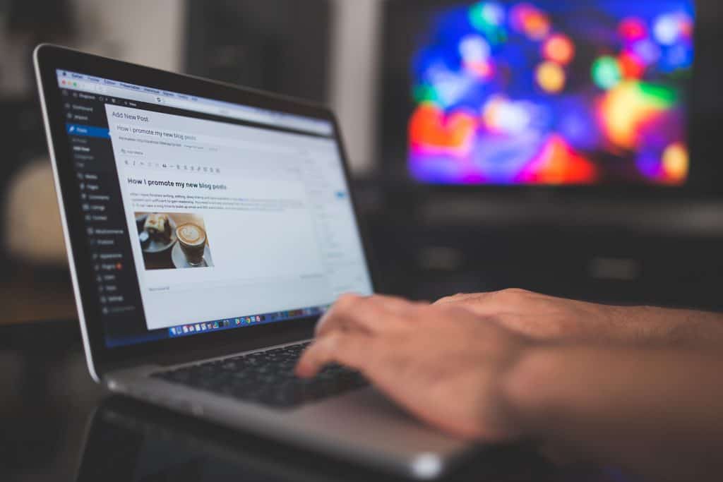 Hands typing a new blog post in the WordPress editor on a laptop