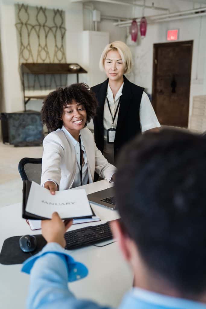 Freelancer handing a proposal document to a client across a desk while applying how to write winning proposals