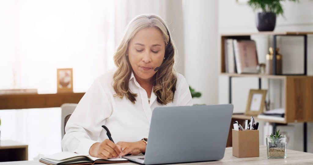 Virtual assistant working remotely with a laptop, headset and notebook
