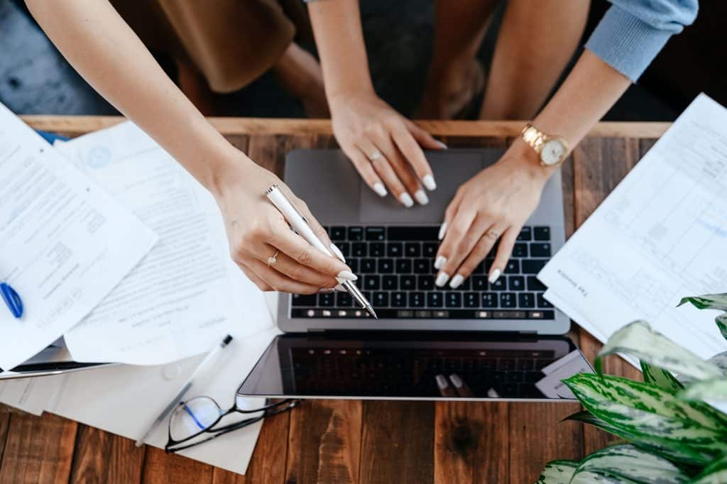 Two freelancers reviewing financial documents and a laptop together at a desk