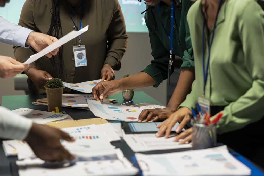 Team of colleagues reviewing charts and documents together at a table during a briefing