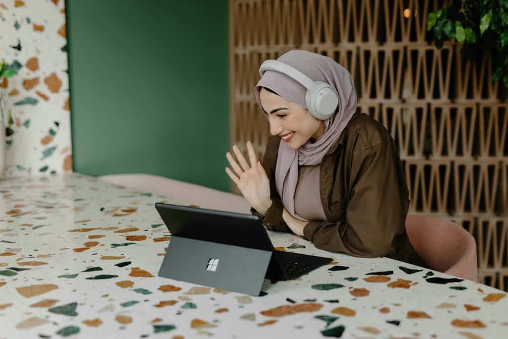 Is Upwork worth it? A lady with headphones says hi online to a client via her tablet.